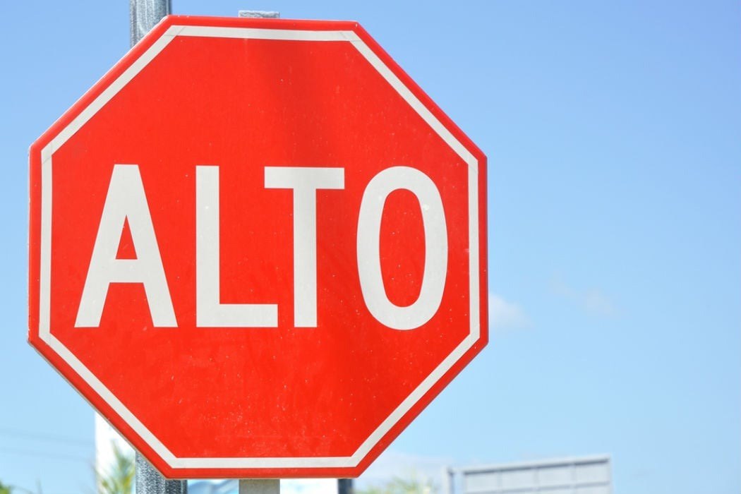 Señal octagonal roja con la palabra ALTO sobre el cielo.