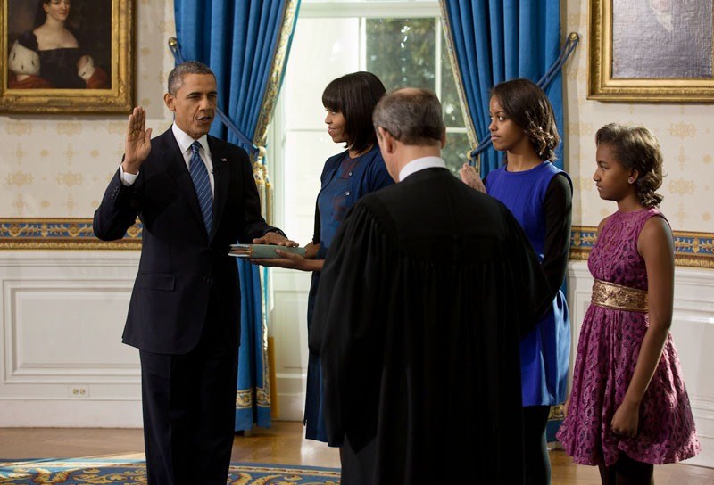 Barack Obama levanta la mano durante el juramento, junto a su familia.